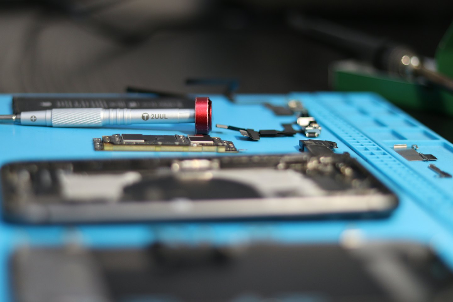 Technik naprawiający smartfon przy użyciu małych narzędzi i komponentów.